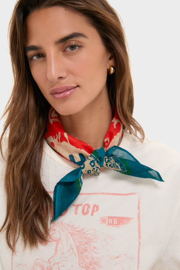 Young woman wears the HB x Tuckernuck Texas Strong Scarf featuring vibrant patterns, paired effortlessly with gold hoops and a classic white T-shirt, exuding a high-end, fun style.