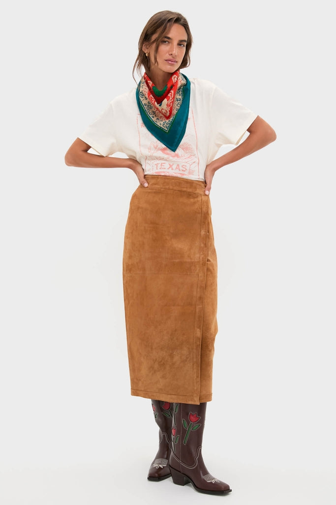 Woman wearing HB x Tuckernuck Texas Strong Scarf, styled effortlessly with a graphic T-shirt, camel suede skirt, and embroidered cowboy boots; exuding classic, high-end fashion.