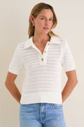 Woman in an Ivory Crochet Cotton Asher Polo, featuring a classic three-button placket and relaxed fit, paired with medium-wash jeans, exuding an effortless, high-end style.