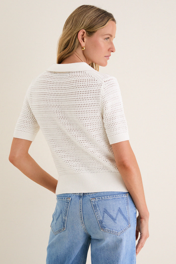 Woman in an Ivory Crochet Cotton Asher Polo, showcasing an effortlessly classic style with a relaxed fit and three-button placket, epitomizing high-end, fun fashion.
