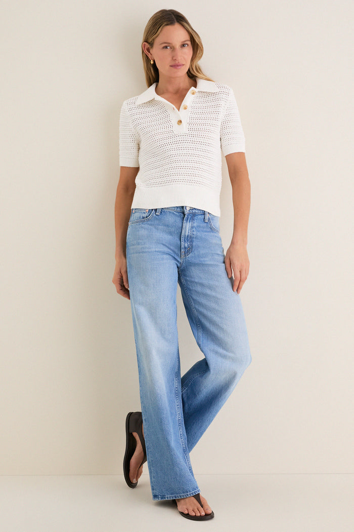 Woman models the Ivory Crochet Cotton Asher Polo, a classic, effortless knit with a relaxed fit and three-button placket, styled with jeans and sandals.