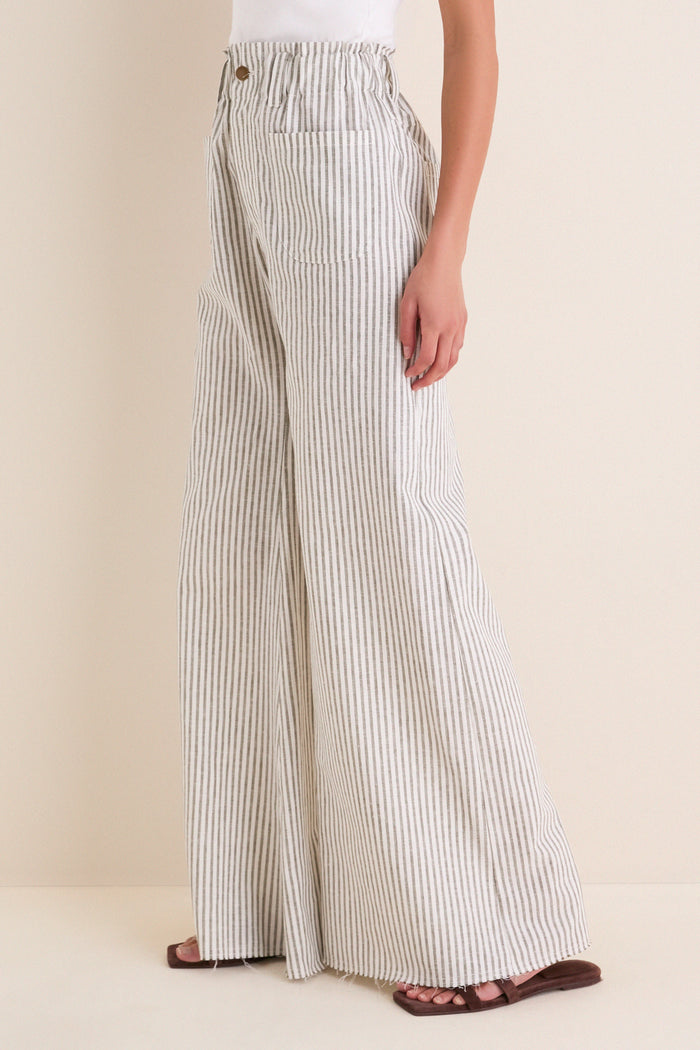 Juniper Stripe Linen Tulip Wide Leg Pant: Classic, effortless high-waisted trousers with a relaxed fit, paper-bag waistband, and raw-edge hem, styled with brown sandals for a fun, high-end look.