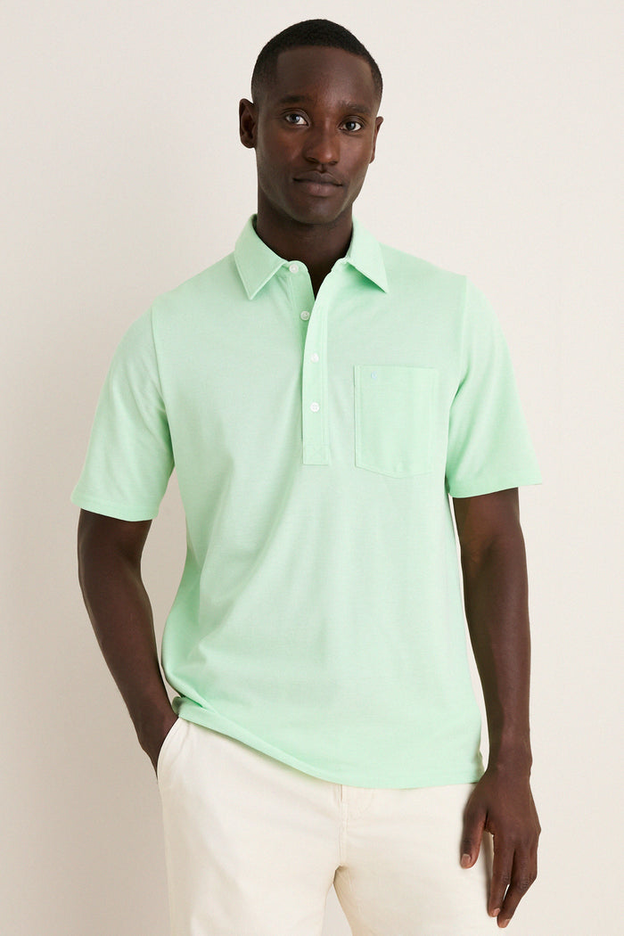Young Black man wearing the classic Key West Oxford Pique Players Shirt, featuring a spread collar and chest flap pocket, paired effortlessly with trousers for a fun, high-end look.