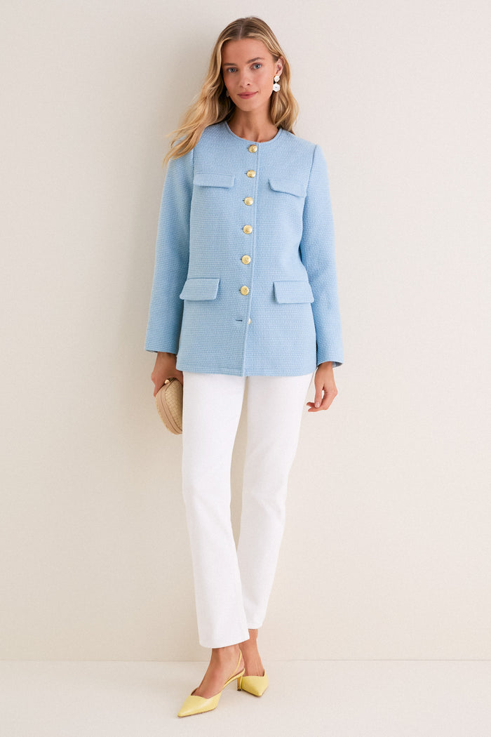 Model in a classic Light Blue Tweed Jennings Jacket with gold buttons and flap pockets, styled effortlessly with white pants and yellow heels for a high-end, fun look.