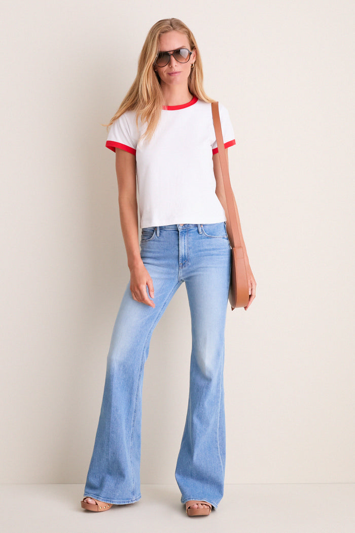 Woman in bell-bottom jeans and a white ringer T-shirt wearing Light Havana Cats 5000 Classic Sunglasses, embodying effortless, high-end style with a fun, modern twist.