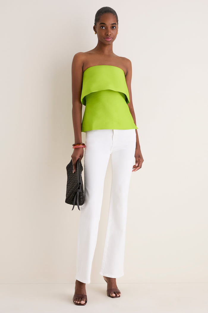 Model in a classic, high-end Lime Felix Satin Strapless Top with a fold-over neckline, paired with effortless white jeans, exuding fun sophistication.