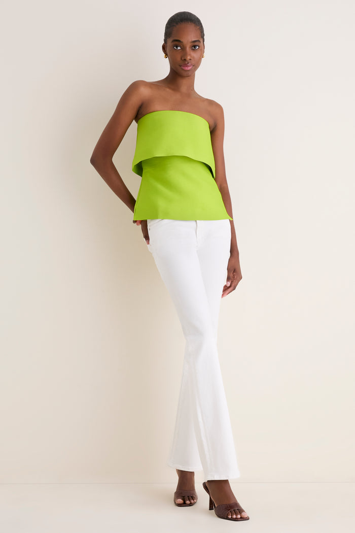 Model in classic, effortless Lime Felix Satin Strapless Top with fold-over neckline, paired with high-end white jeans and heels for a fun, chic look.