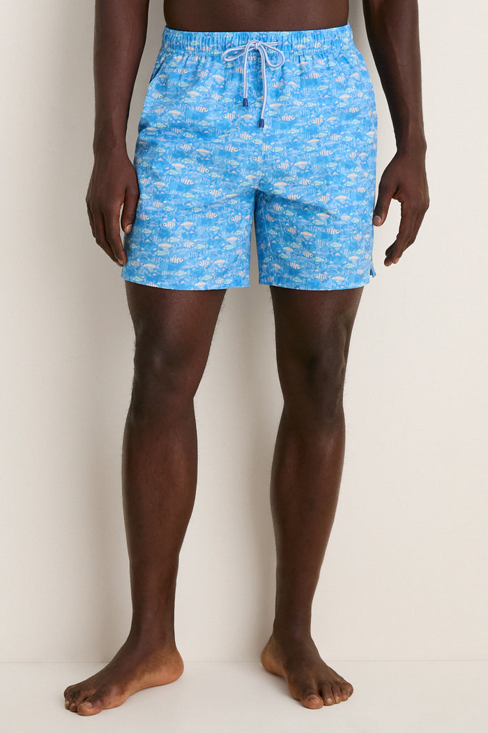 Barefoot person in Marina Blue Sunfish Swim Trunk, showcasing classic, effortless style with fun fish pattern, elastic waistband, and quick-drying, high-end fabric.