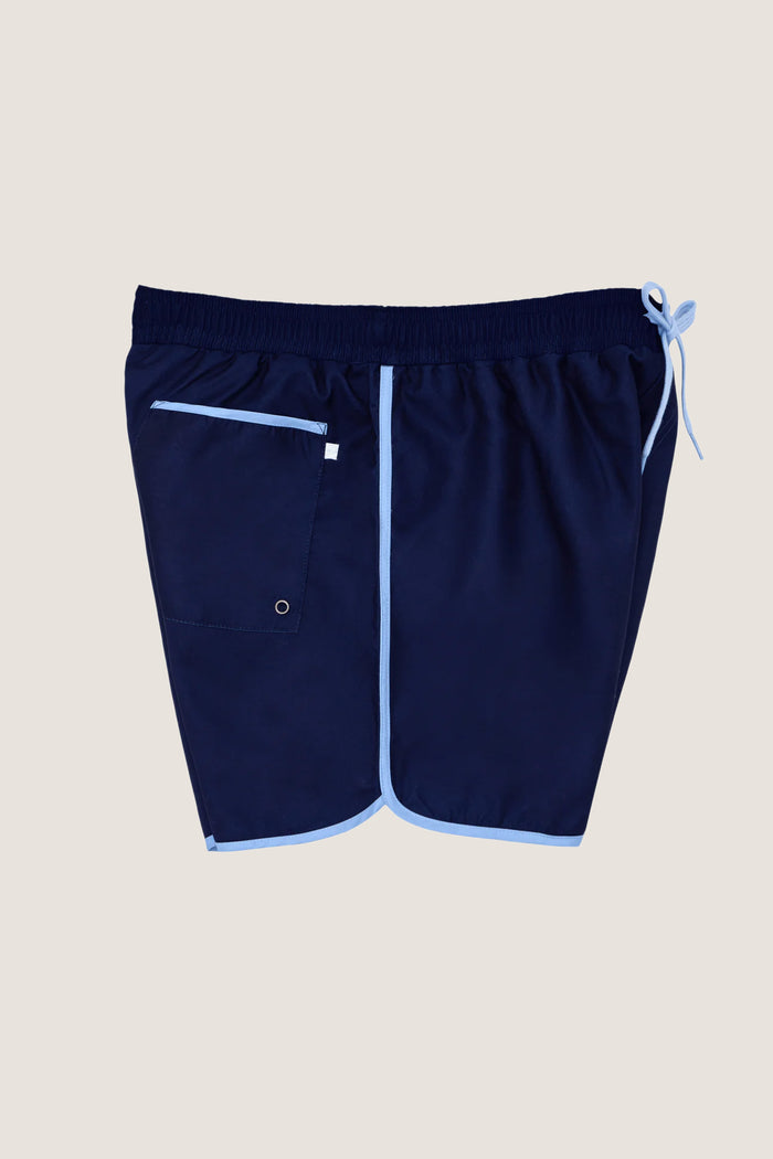 Navy Boardie swim trunks with light-blue trim, featuring an elastic drawstring waist, side pockets, and a back patch pocket, offer a classic, effortless, and fun high-end style.