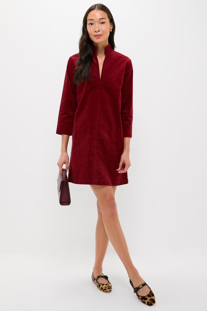 Model wears the Merlot Corduroy Clifton Dress, a classic, effortless A-line with a stand collar and V-neck, holding a matching clutch. Paired with leopard-print Mary Jane flats.