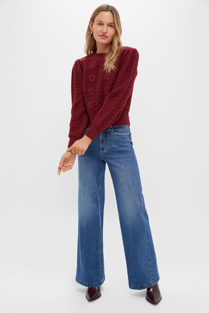 Woman in a classic, deep burgundy Merlot Embroidered Floral Frankie Sweater, paired with wide-leg jeans and ankle boots, exuding an effortless, high-end, fun style.