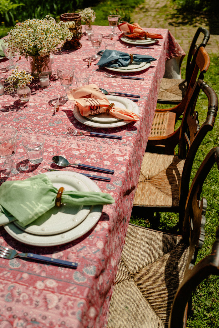 A summer table set with a red tablecloth and colorful napkins.