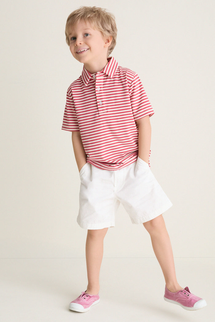 Young blond boy wearing the classic Nantucket Red and Creme Le Club Polo with red and white stripes, exuding effortless fun and high-end style.