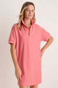 Woman standing in front of a white backdrop in a red polo dress.