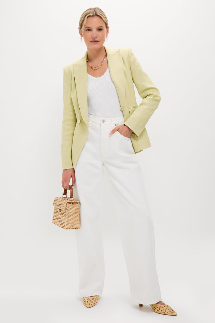 Model in a classic, effortless ensemble featuring high-end Natural Cleo Loop Heels, styled with a pastel-green blazer, white jeans, and a woven straw handbag.