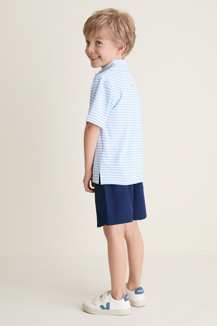 Young boy in profile wearing Nautical Navy Le Club Short and striped polo, embodying classic, effortless style with high-end, fun appeal. Perfect for polished, everyday wear.
