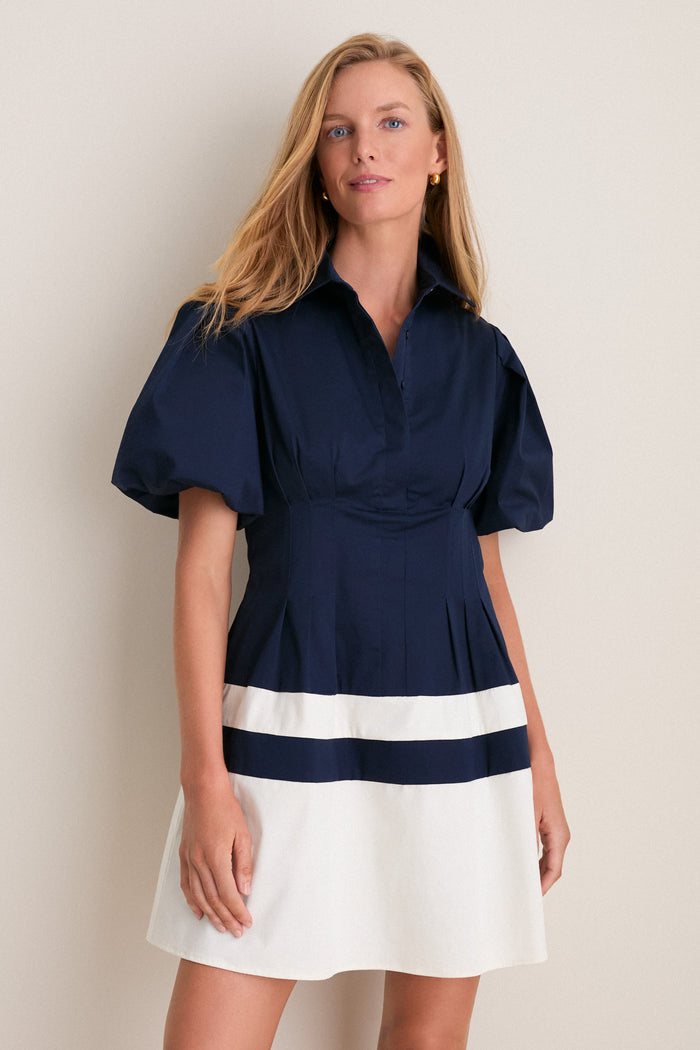 Woman wearing the Navy and White Stripe Mini Delaney Dress, featuring a classic navy top with puffed sleeves and an effortless white skirt with navy stripes, embodying high-end, fun style.