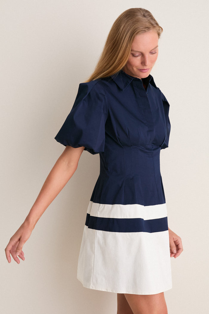 Woman wearing the Navy and White Stripe Mini Delaney Dress, showcasing a classic, effortless look with a navy top and playful stripe skirt, embodying Tuckernuck's fun, high-end style.