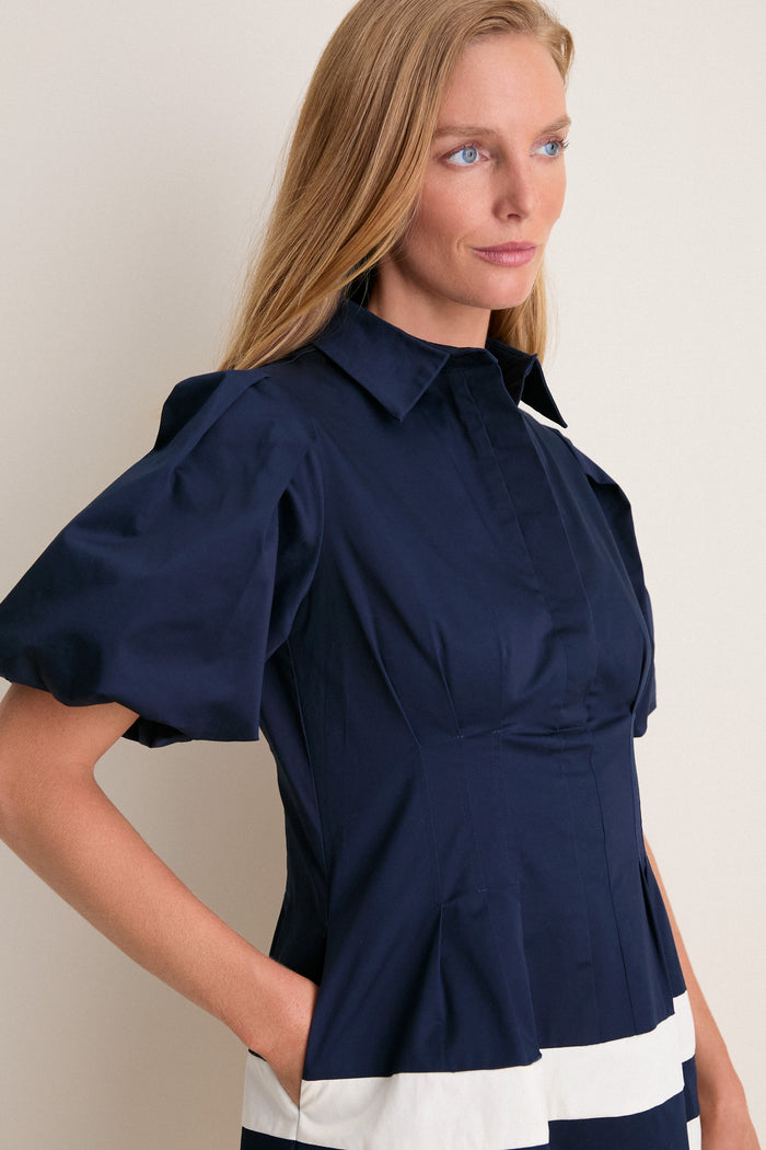 Woman in a classic Navy and White Stripe Mini Delaney Dress with a pointed collar and puffed sleeves, exuding an effortless and fun high-end style.