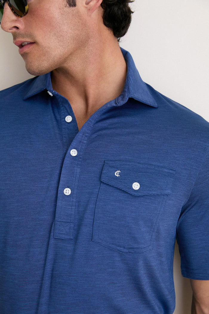 Close-up of a man wearing the classic Navy Captain Heather Performance Sport Players Shirt, featuring a chest pocket and effortless short-sleeve style with tortoiseshell sunglasses.