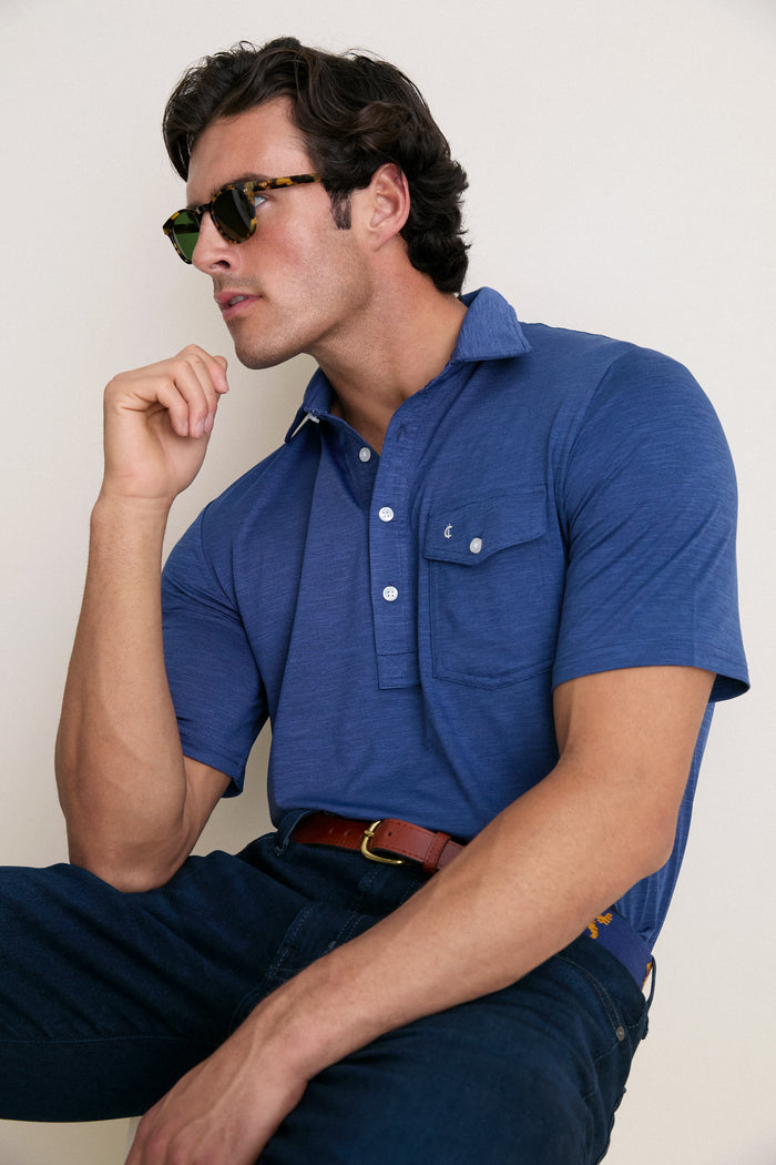 Young man in tortoiseshell sunglasses models the classic Navy Captain Heather Performance Sport Players Shirt, featuring a casual, effortless style with a 4-button placket and chest pocket.