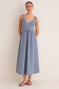 Navy Gingham Sloan Maxi Dress: Effortless and classic, this sleeveless sundress features a V-neck, tie straps, and smocked back, styled with pearl necklace and tan sandals.