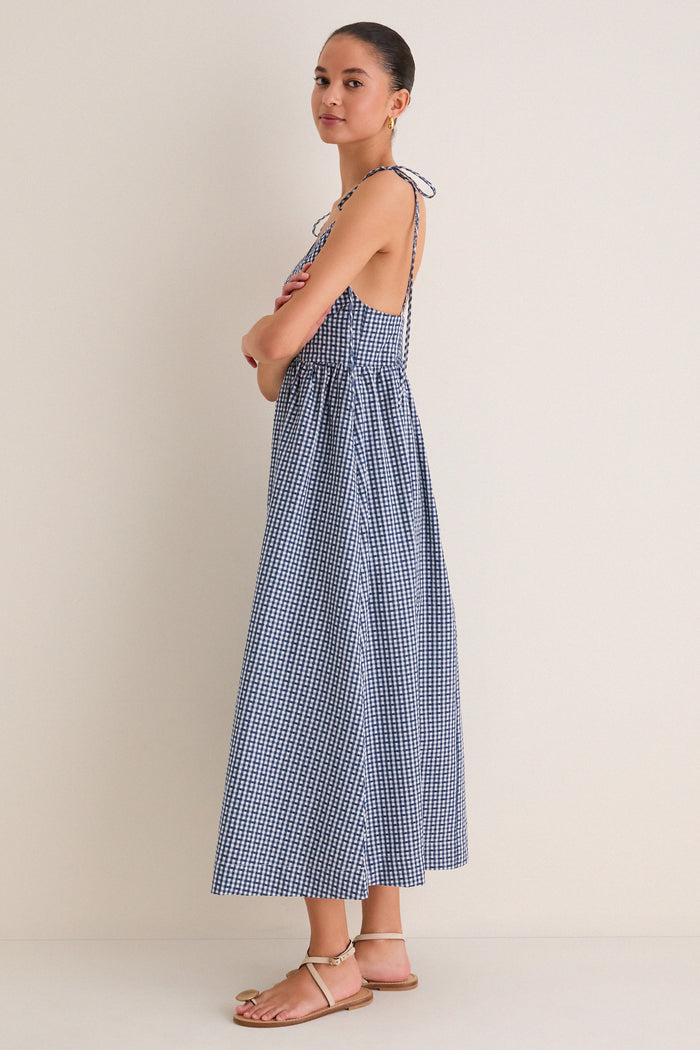 Navy Gingham Sloan Maxi Dress: A classic and effortless ankle-length dress featuring tie straps and a smocked back, styled with fun tan sandals for a high-end look.