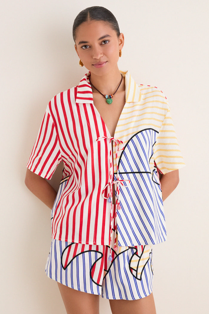 Young woman in a classic, effortless Navy Stripes Off-White Tie Front Blouse with playful multi-colored stripes, embodying high-end, fun style.