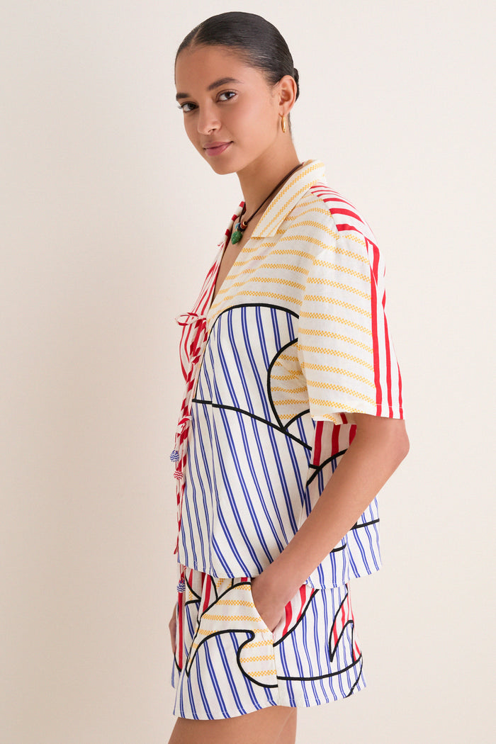 Young woman wearing the classic, effortless Navy Stripes Off-White Tie Front Blouse, featuring fun multi-colored stripes and high-end details, exuding a relaxed, playful charm.