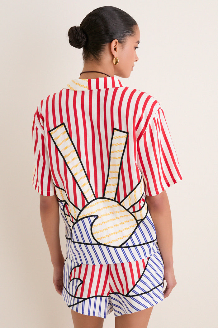 Model in a classic, effortless Navy Stripes Off-White Tie Front Blouse, featuring playful sun motif and fun, high-end striped pattern, embodying relaxed, confident style.