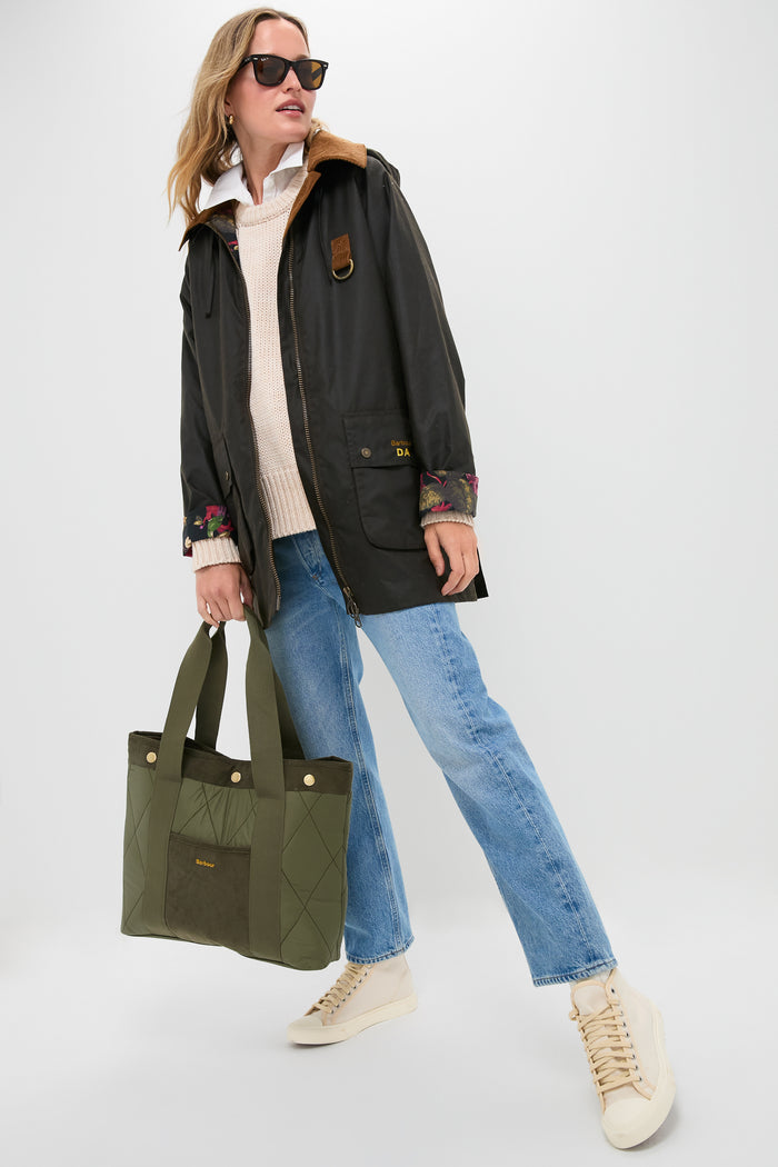 Person styled in classic fashion holds the Olive Healy Tote Bag, showcasing its quilted design and snap closure, embodying effortless, high-end style and everyday functionality.