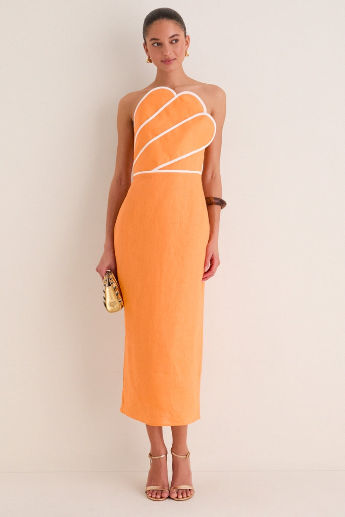 Model wearing the Orange Linen Clementine Maxi Dress: a classic, strapless midi with an asymmetrical neckline, white piping, and a smocked back, styled with gold accessories.