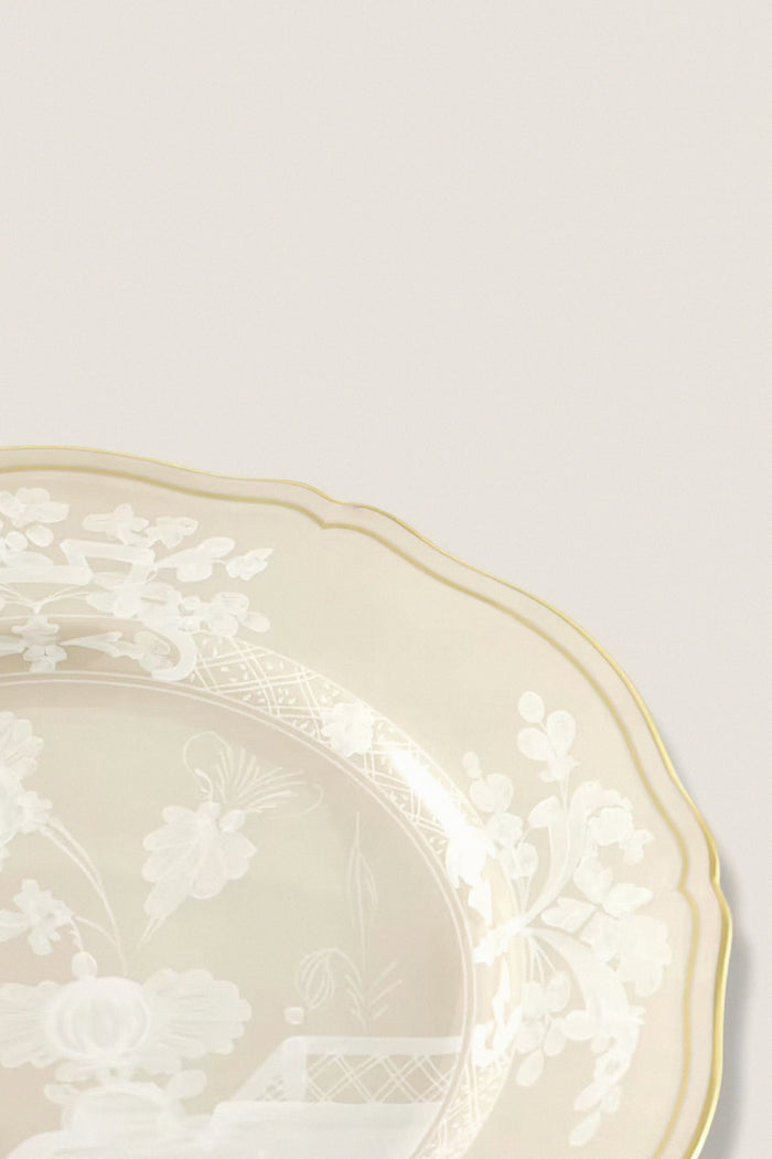 Oriente Italiano Meringa Dinner Plate, a classic porcelain piece with a gold-edged scalloped rim and intricate white floral design, embodies effortless elegance and high-end craftsmanship.