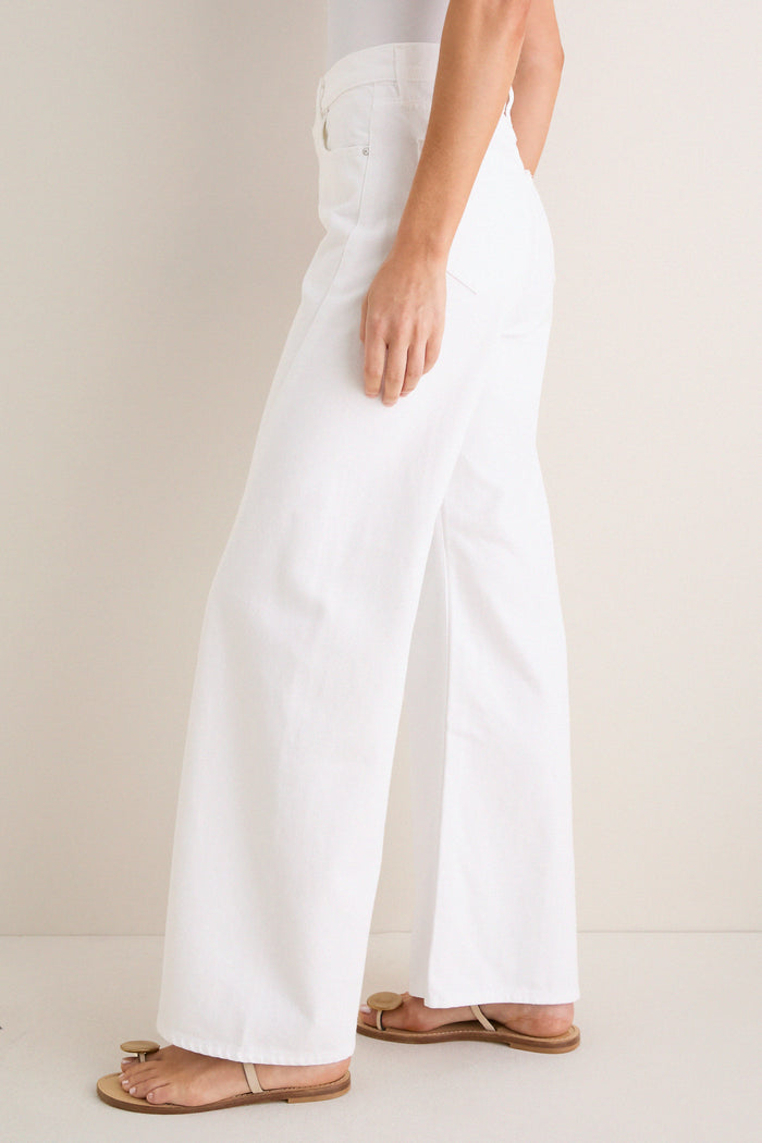 Person wearing Pinch of Salt The Lemon Twist Skimp, classic high-waisted, wide-leg jeans with raw hem, paired with effortless flat sandals for a fun, high-end look.