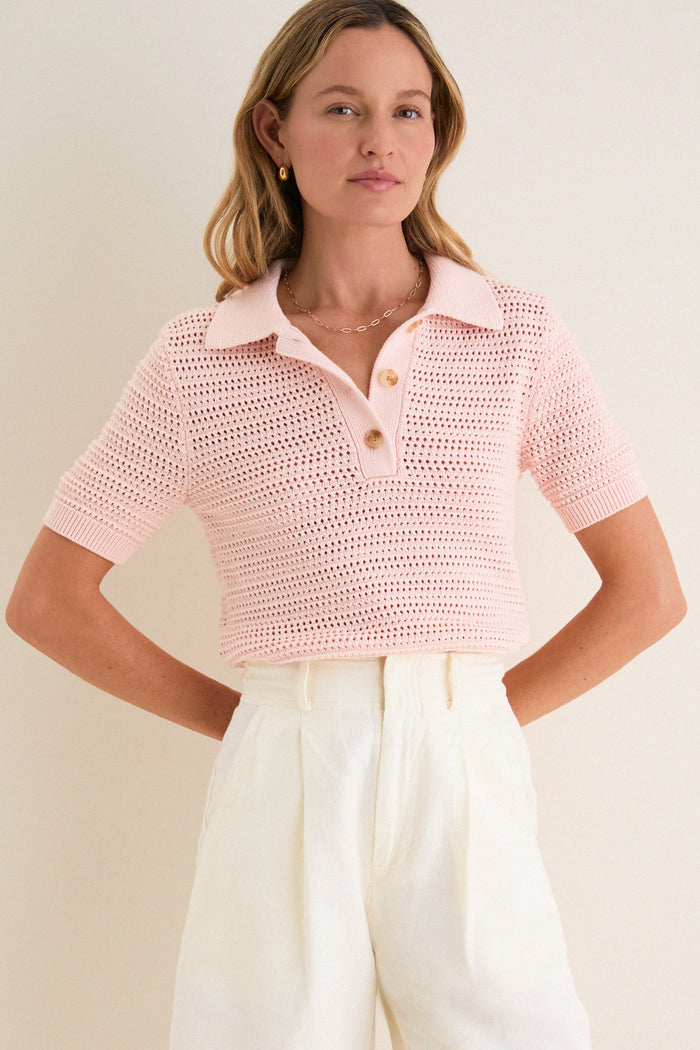 Woman wearing the Pink Crochet Cotton Asher Polo, a classic, effortless short-sleeve sweater with a relaxed fit, paired with high-waisted trousers for a high-end, fun look.