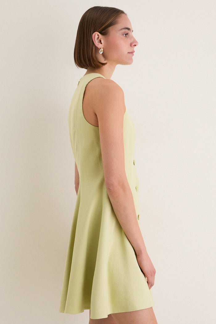 Young woman in profile wears the classic Pistachio Steiner Dress, showcasing its effortless A-line silhouette and high-end button-down detailing, perfect for fun, stylish outings.