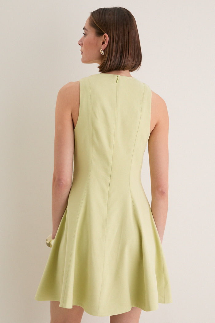 Woman in a classic, pale-green sleeveless Pistachio Steiner Dress with a fit-and-flare style, showcasing effortless elegance and fun, high-end fashion.
