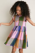 Young girl in classic Plaid Madras Alyssa Dress with patch pockets, ruffle detailing, and silver buttons, embodying effortless, fun style for high-end comfort.