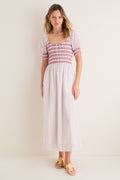 Model wearing the Poppy Half Drop White Madeline Nap Dress, featuring a smocked bodice, square neckline, and puffed sleeves. Ankle-length, effortless, high-end style with a classic, fun floral print.