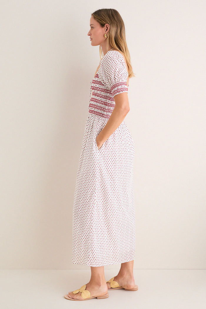 Woman in profile wearing the classic, effortless Poppy Half Drop White Madeline Nap Dress with puffed sleeves, smocked bodice, and fun floral motifs; styled with high-end accessories.