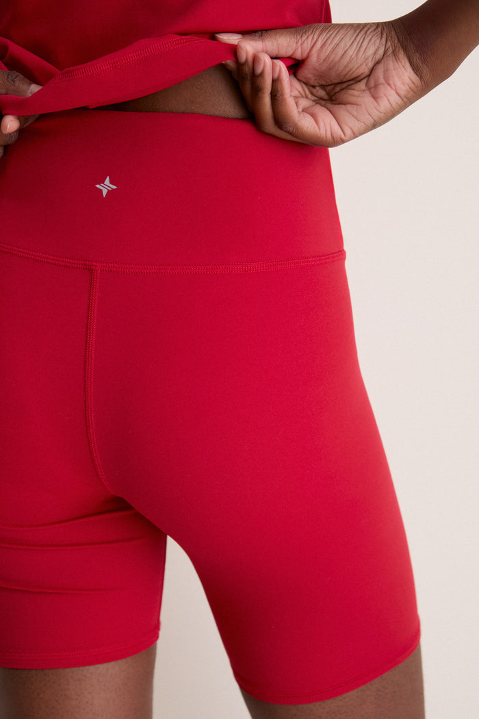 Red Compression Spandex Mac Bike Short showcasing a classic, effortless high rise fit with a reflective logo and hidden waistband pocket, ideal for fun, high-end athleisure styling.