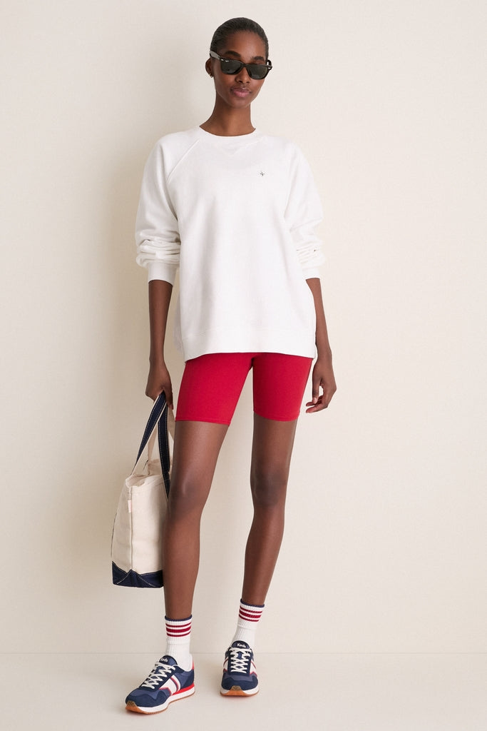 Young woman in classic, high-end Red Compression Spandex Mac Bike Short, showcasing an effortless athleisure look with a chic oversized sweatshirt and trendy accessories.