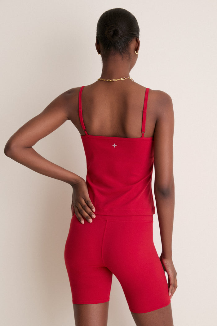 Woman in a classic, effortless Red Compression Spandex Sofia Cami with adjustable straps and built-in shelf bra, embodying a high-end, fun style.