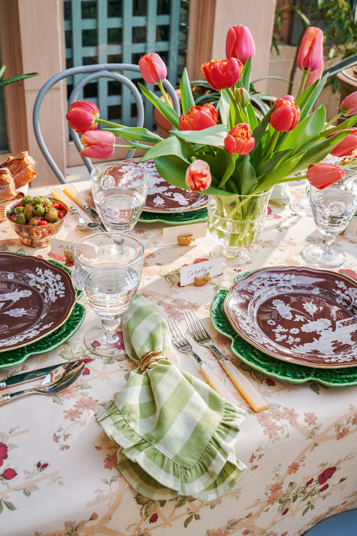 Rose Trellis Tablecloth elegantly drapes an outdoor dining table with tulips, vintage flatware, gingham napkins, creating a classic, effortless, high-end spring brunch setting.