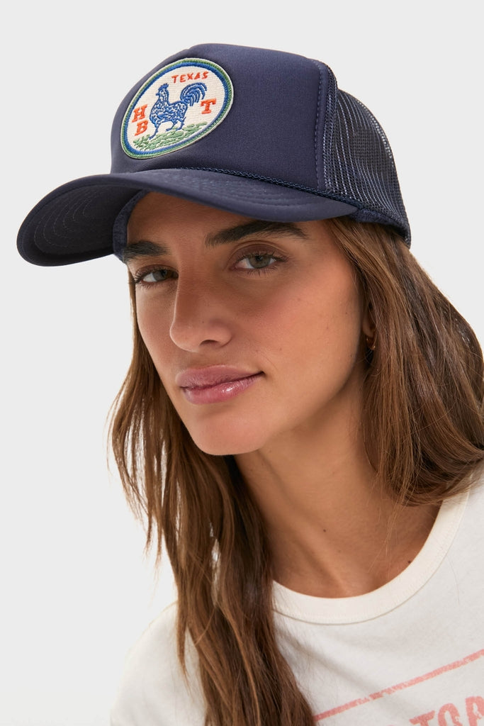 Young woman wears the classic Round Top Trucker Hat featuring a circular Texas rooster patch. This high-end, effortless accessory is perfect for fun, casual outings.