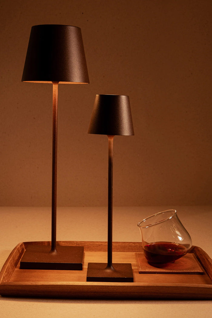 Rust Poldina Pro Table Micro Lamp, classic and cordless, stands elegantly on a tray, embodying effortless high-end design, perfect for fun indoor and outdoor illumination.