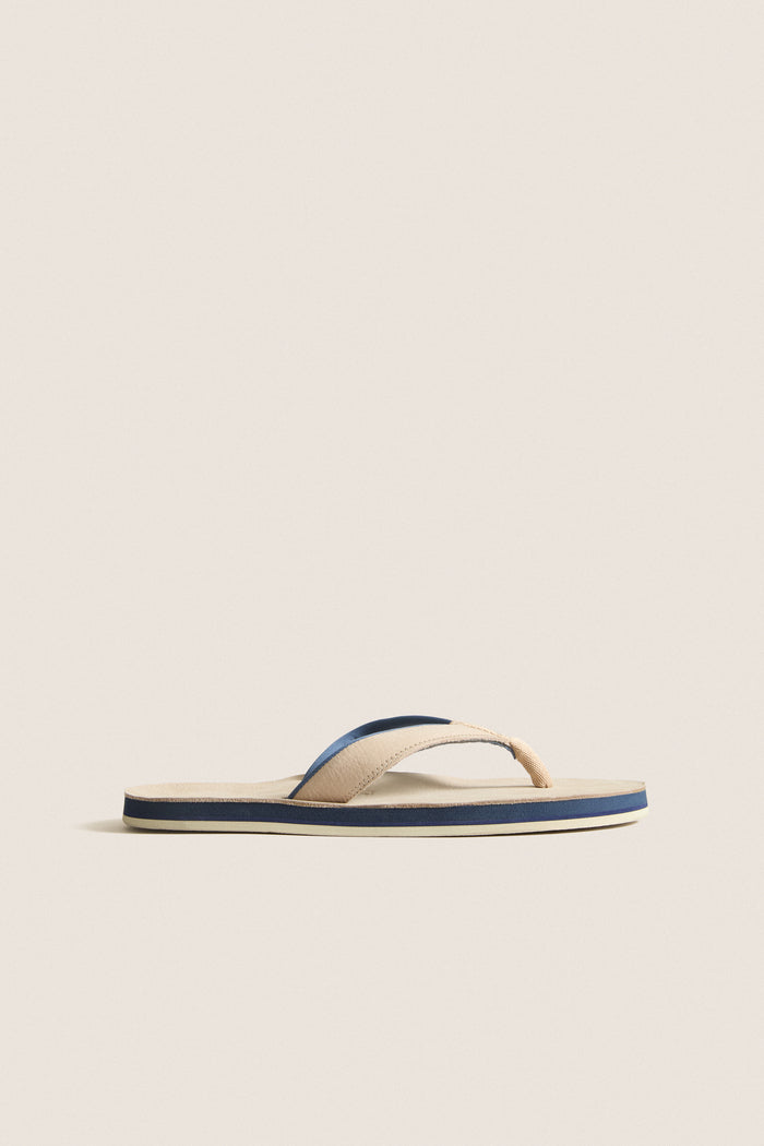 Classic Sand Pier Pebbled Leather Sandal with beige straps, navy and cream striped sole, offering effortless style and high-end comfort for fun, relaxed outings.