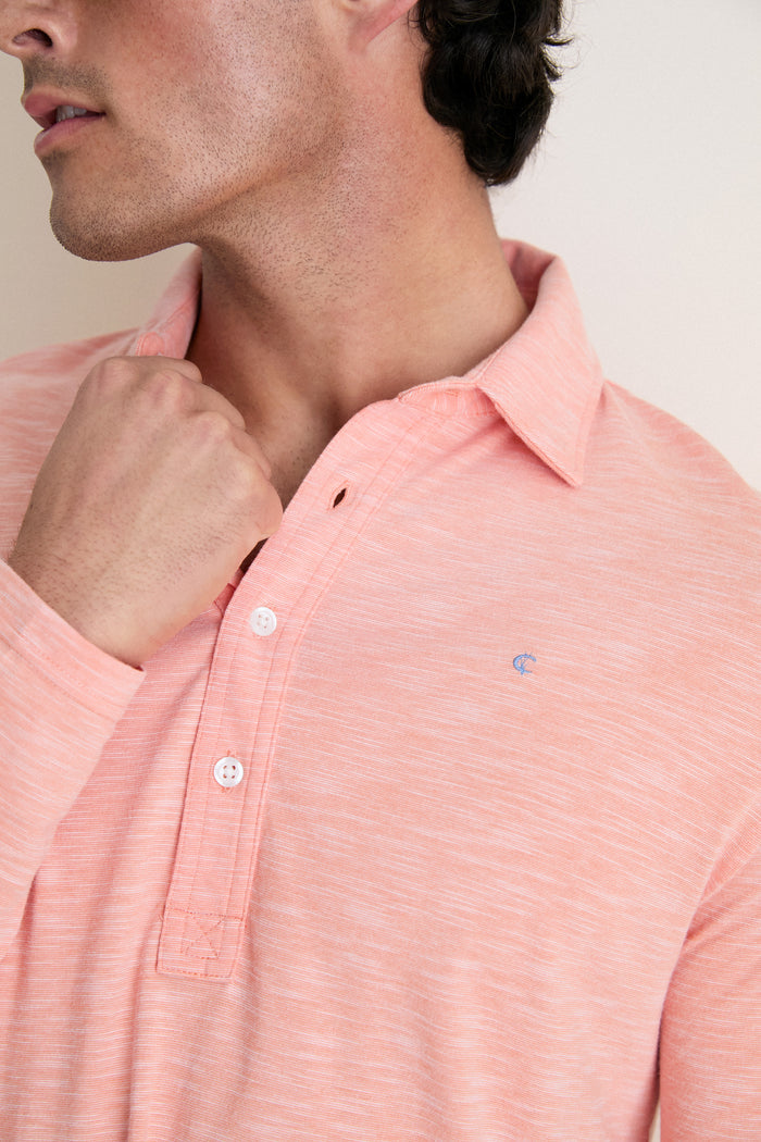 Man in a classic, light salmon-pink Shell Phone Brrr Long Sleeve Range Polo, showcasing its effortless style, cooling technology, and high-end detailing with a small embroidered logo.