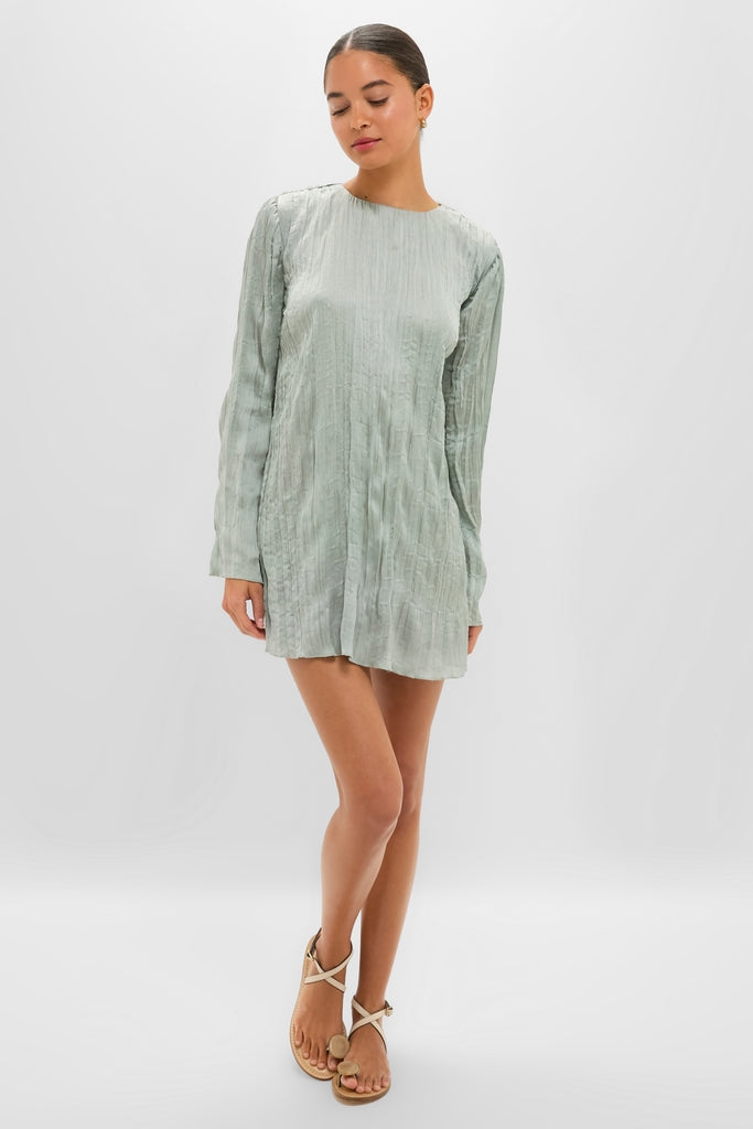 Young woman models the classic Silver Sage Kona Dress, a crinkle-textured mini with a high neckline, embodying effortless style and fun sophistication.