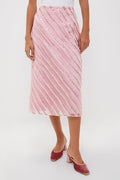 A person wears a Hyacinth House light pink shimmer stripe skirt with matching pink heeled mules, creating a festive look perfect for a holiday party.